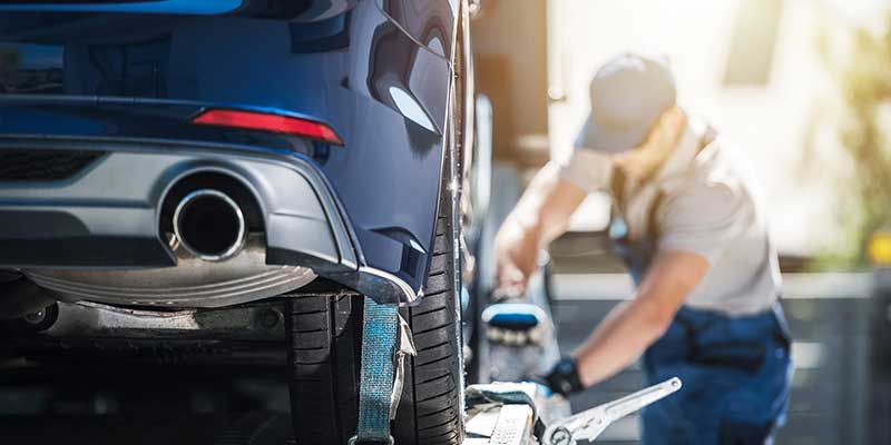 Rear view of a vehicle being loaded on a truck for a delievery