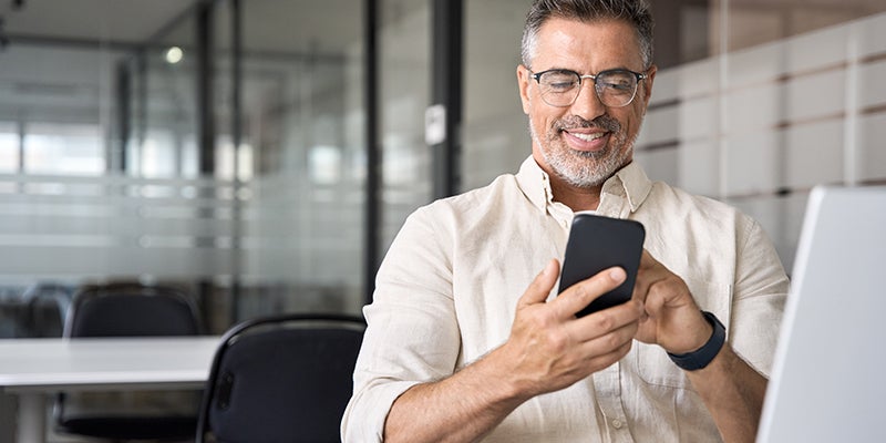 A smiling man using a smartphone